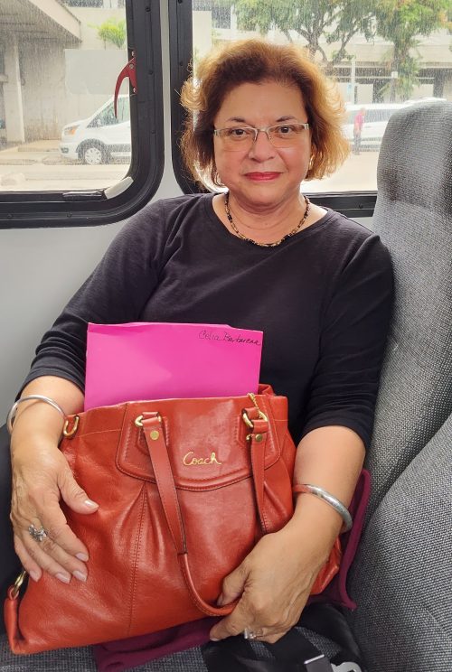 woman sitting in a van holding an orange purse